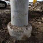 Betonowy słup osadzony w okrągłej podstawie podczas prac ziemnych na placu budowy