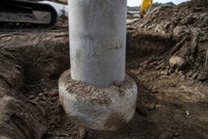 Betonowy słup osadzony w okrągłej podstawie podczas prac ziemnych na placu budowy