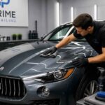 Pracownik studia detailingowego poleruje maskę ciemnego Maserati w profesjonalnym garażu